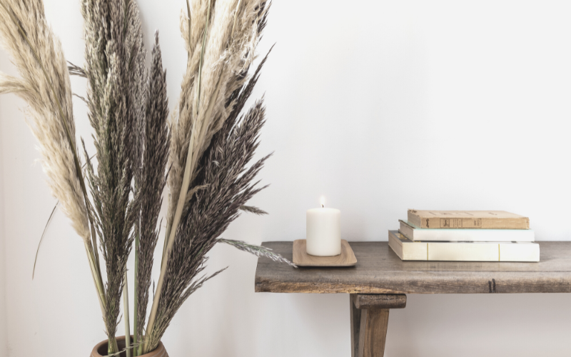 Why you should simplify your life. Image shows a table with books and a candle next to a plant. 