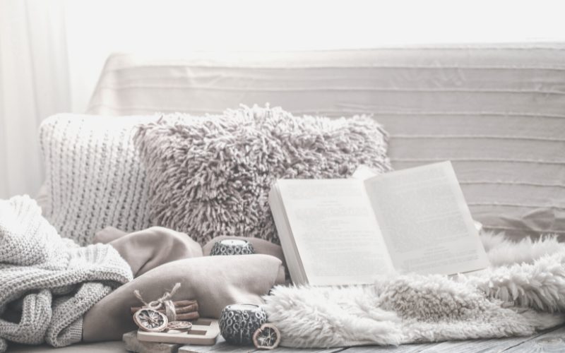 Learn how to simplify your life. Image shows a sofa decorated with book, candles and pillows.